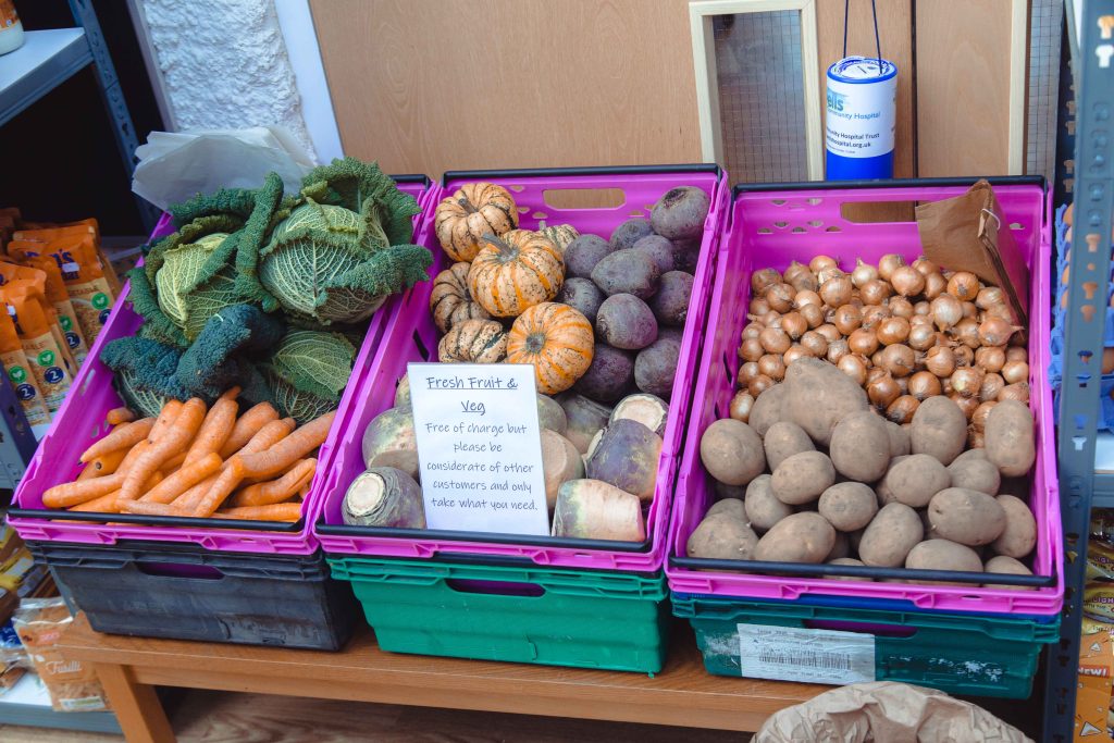 Fresh vegetables in pink crates in a community cafe.