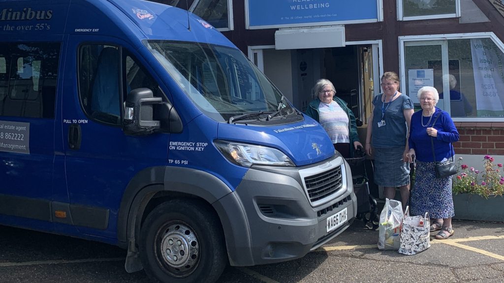 Three women stand outside The Coastal Health and Wellbeing building with full shopping bags. The Old Hospital is on the of the stopping points for the coastal community supermarket.